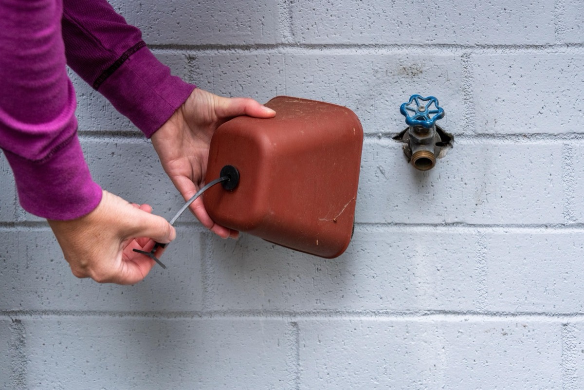 Hands fitting an insulated cover over an outdoor faucet